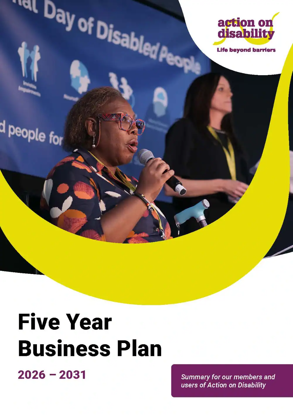 A woman speaks into a microphone onstage beside another woman at an event for disabled people. The cover text reads: "Five Year Business Plan 2026–2031" by Action on Disability.