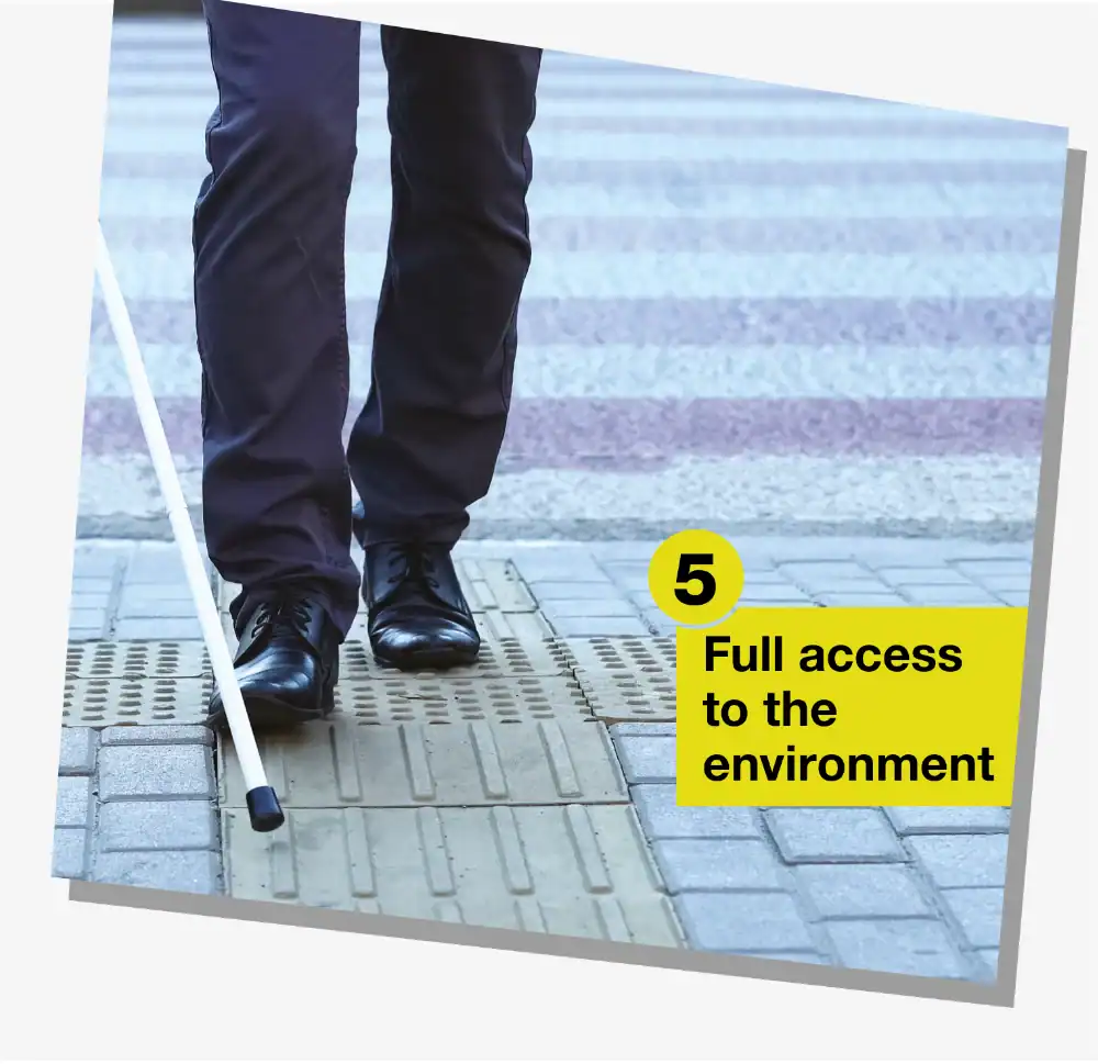 A person using a white cane walks on tactile paving towards a crosswalk. A yellow box reads: "5 Full access to the environment.